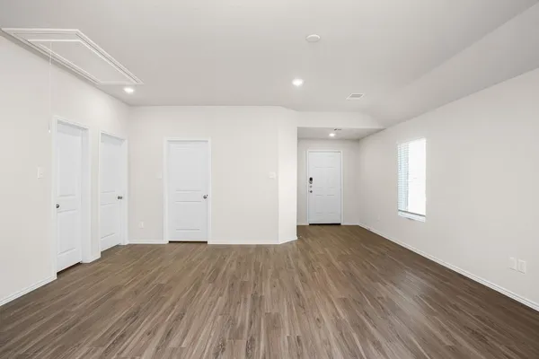 a view of an empty room with wooden floor and window