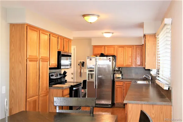 a kitchen with stainless steel appliances a refrigerator a sink a stove and white cabinets with wooden floor