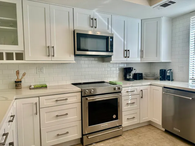 a kitchen with stainless steel appliances granite countertop white cabinets a sink and dishwasher