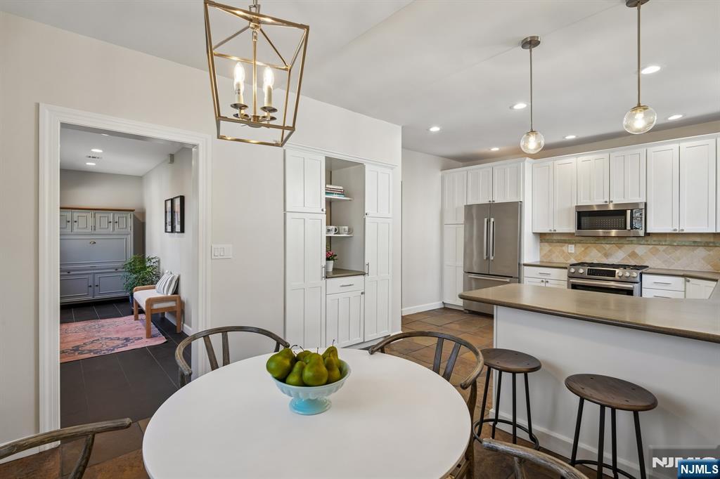 115 Park Street Montclair, NJ 07042 - Photo 24 of 45 a kitchen with stainless steel appliances a dining table chairs and white cabinets