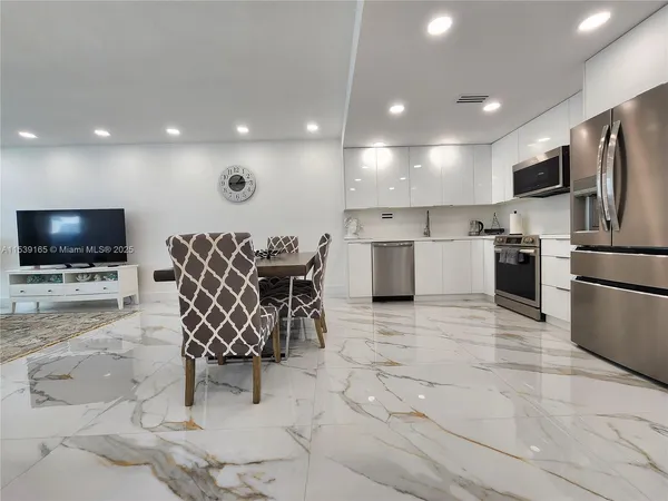 a kitchen with stainless steel appliances kitchen island granite countertop a sink and a refrigerator