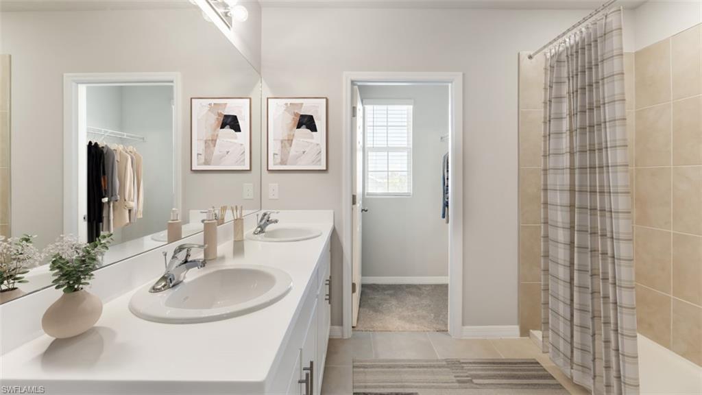 17764 Shade Tree Loop Punta Gorda, FL 33982 - Photo 11 of 12 Bathroom with light tile patterned flooring, double vanity, and a tile shower