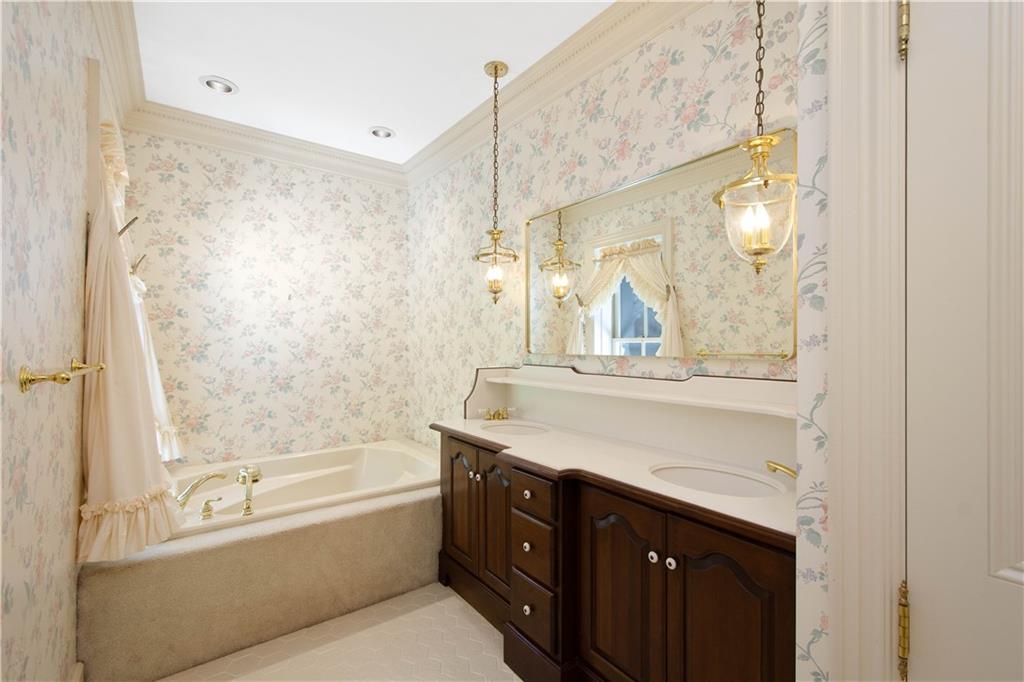 571 West McMurray Road Canonsburg, PA 15317 - Photo 23 of 47 This inviting bathroom captures the home's historic character with vintage-inspired floral wallpaper and warm wood cabinetry. It features a spacious built-in soaking tub, a large vanity with ample storage, and elegant pendant lighting that adds a soft, classic glow to the space.
