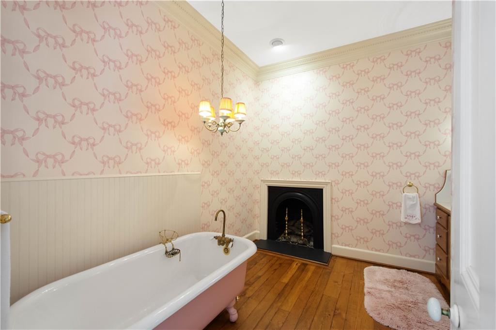 571 West McMurray Road Canonsburg, PA 15317 - Photo 25 of 47 A masterfully restored bathroom that serves as a private sanctuary. Relax in the vintage-inspired clawfoot soaking tub positioned beside a cozy gas fireplace. The room is finished with rich pine floors, elegant floral wallpaper, and a classic chandelier that enhances its historic charm.