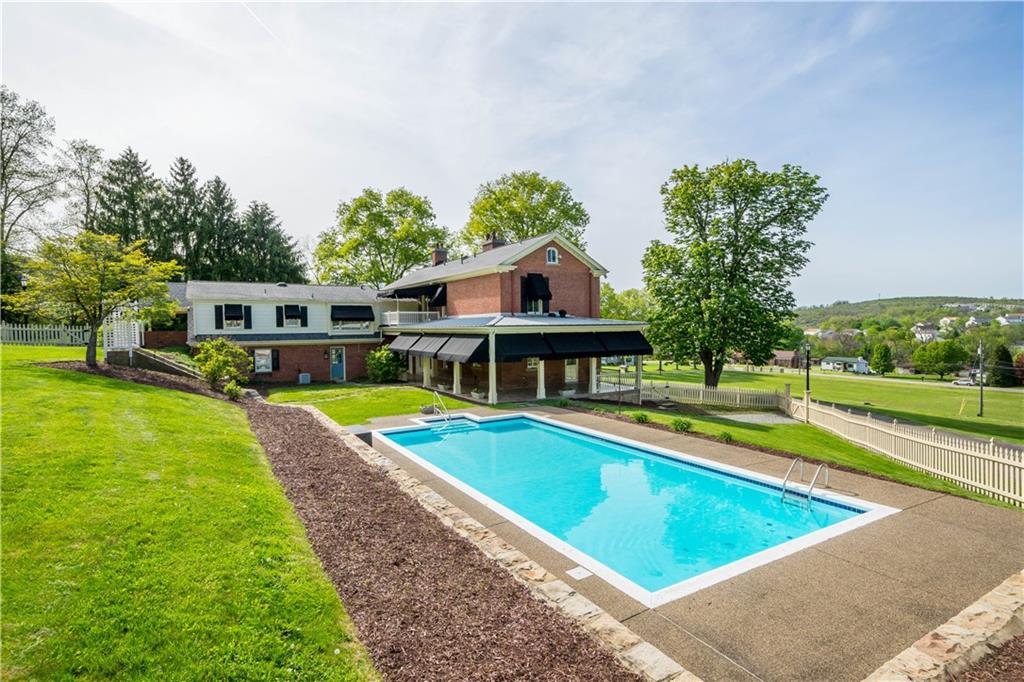 571 West McMurray Road Canonsburg, PA 15317 - Photo 39 of 47 Enjoy a private resort experience in your own backyard. This expansive in-ground pool is perfectly positioned adjacent to the covered wrap-around patio, offering a seamless flow for summer entertaining. Surrounded by a spacious concrete deck and a classic white picket fence, it provides a serene setting to overlook the 14-acre estate.