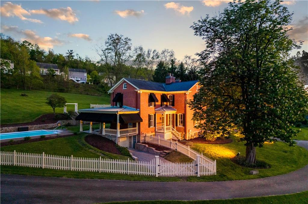 571 West McMurray Road Canonsburg, PA 15317 - Photo 5 of 47 Atmospheric dusk elevation of this historic brick home, featuring a glowing wrap-around porch and professionally lit landscaping. A serene setting that highlights the privacy and prestige of this 14-acre Washington County retreat.