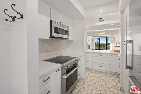 a kitchen with white cabinets and stainless steel appliances