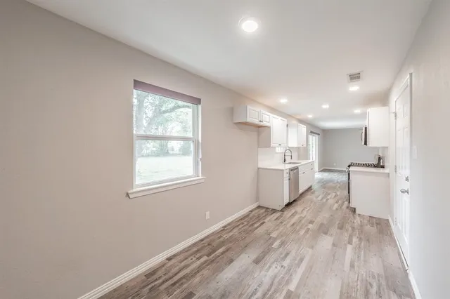 a view of a kitchen with a sink and dishwasher a refrigerator with wooden floor