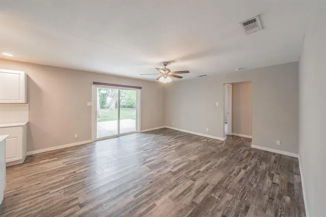 a view of an empty room with a window and wooden floor