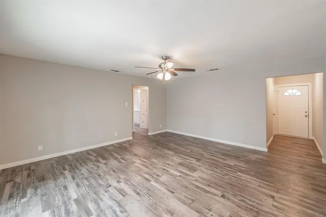 a view of a room with wooden floor and a ceiling fan
