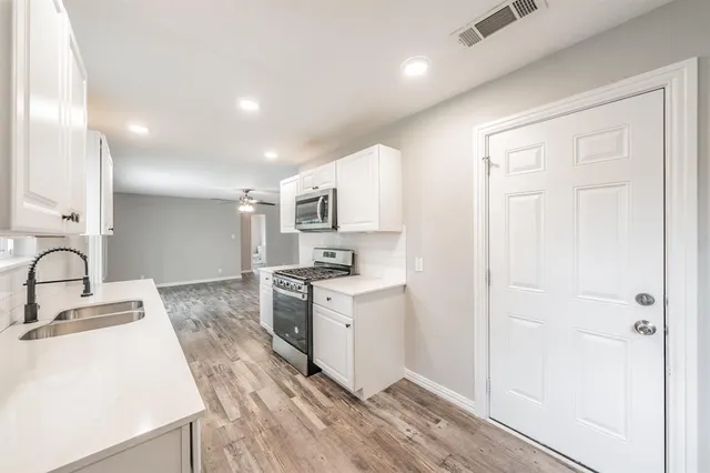 a large kitchen with granite countertop a sink stainless steel appliances and cabinets
