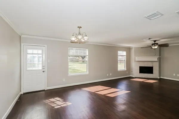 an empty room with wooden floor chandelier and windows
