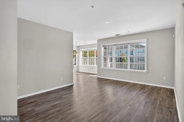 a view of an empty room with wooden floor and windows