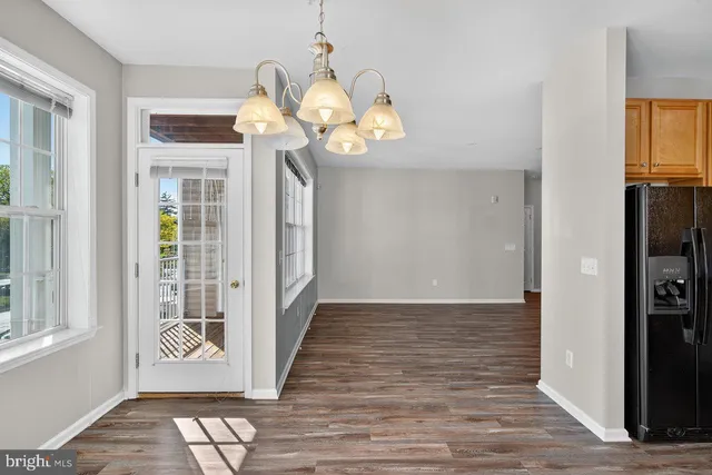 a view of a hallway with wooden floor and a dining room