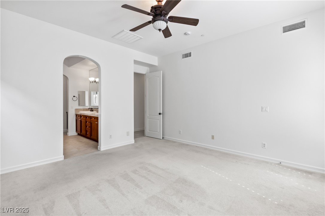 58 Contrada Fiore Drive Henderson, NV 89011 - Photo 22 of 56 Unfurnished bedroom with a ceiling fan, ensuite bathroom, light colored carpet, and arched walkways