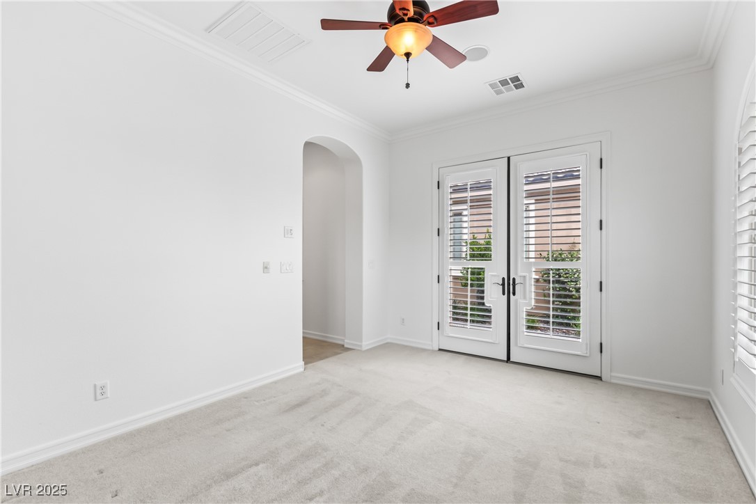 58 Contrada Fiore Drive Henderson, NV 89011 - Photo 29 of 56 Spare room with light carpet, arched walkways, crown molding, french doors, and ceiling fan