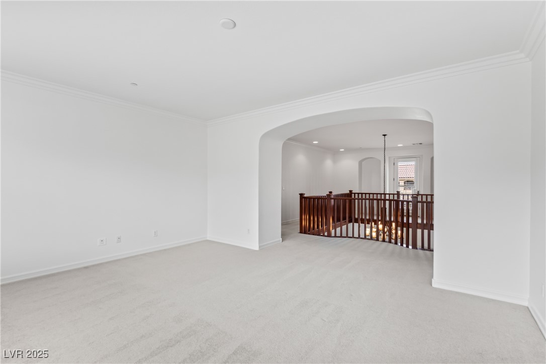 58 Contrada Fiore Drive Henderson, NV 89011 - Photo 35 of 56 Empty room featuring light carpet, recessed lighting, crown molding, and arched walkways
