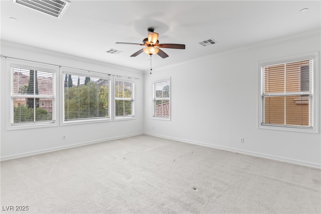 58 Contrada Fiore Drive Henderson, NV 89011 - Photo 41 of 56 Empty room featuring plenty of natural light, ornamental molding, light colored carpet, and a ceiling fan