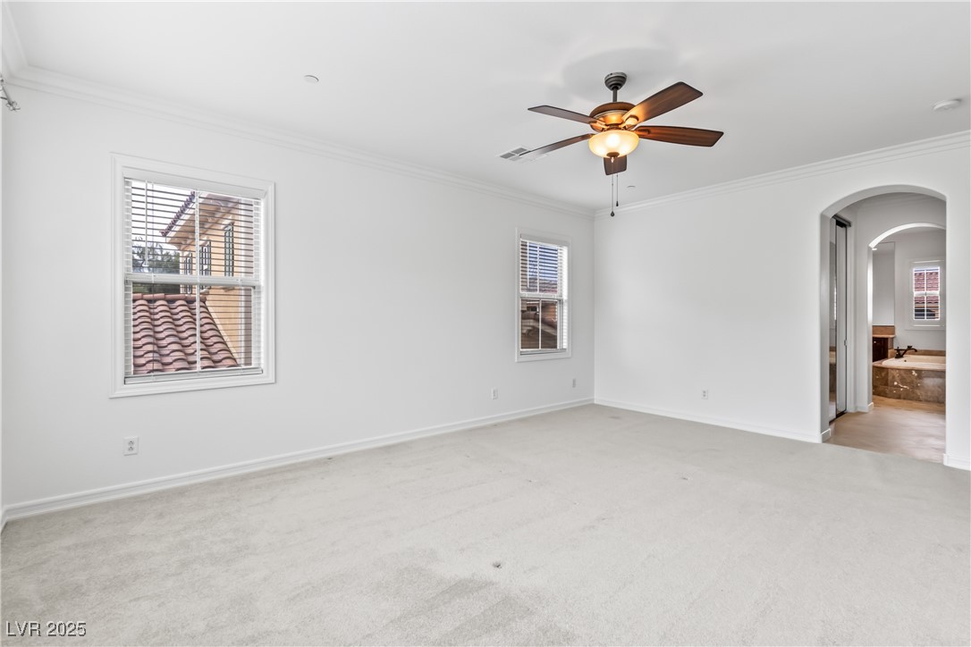 58 Contrada Fiore Drive Henderson, NV 89011 - Photo 44 of 56 Unfurnished room featuring ornamental molding, arched walkways, plenty of natural light, light colored carpet, and ceiling fan