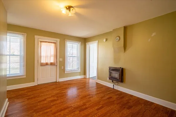 a view of an empty room with wooden floor and a window