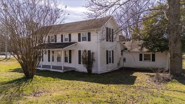 a view of a white house with a yard covered with snow