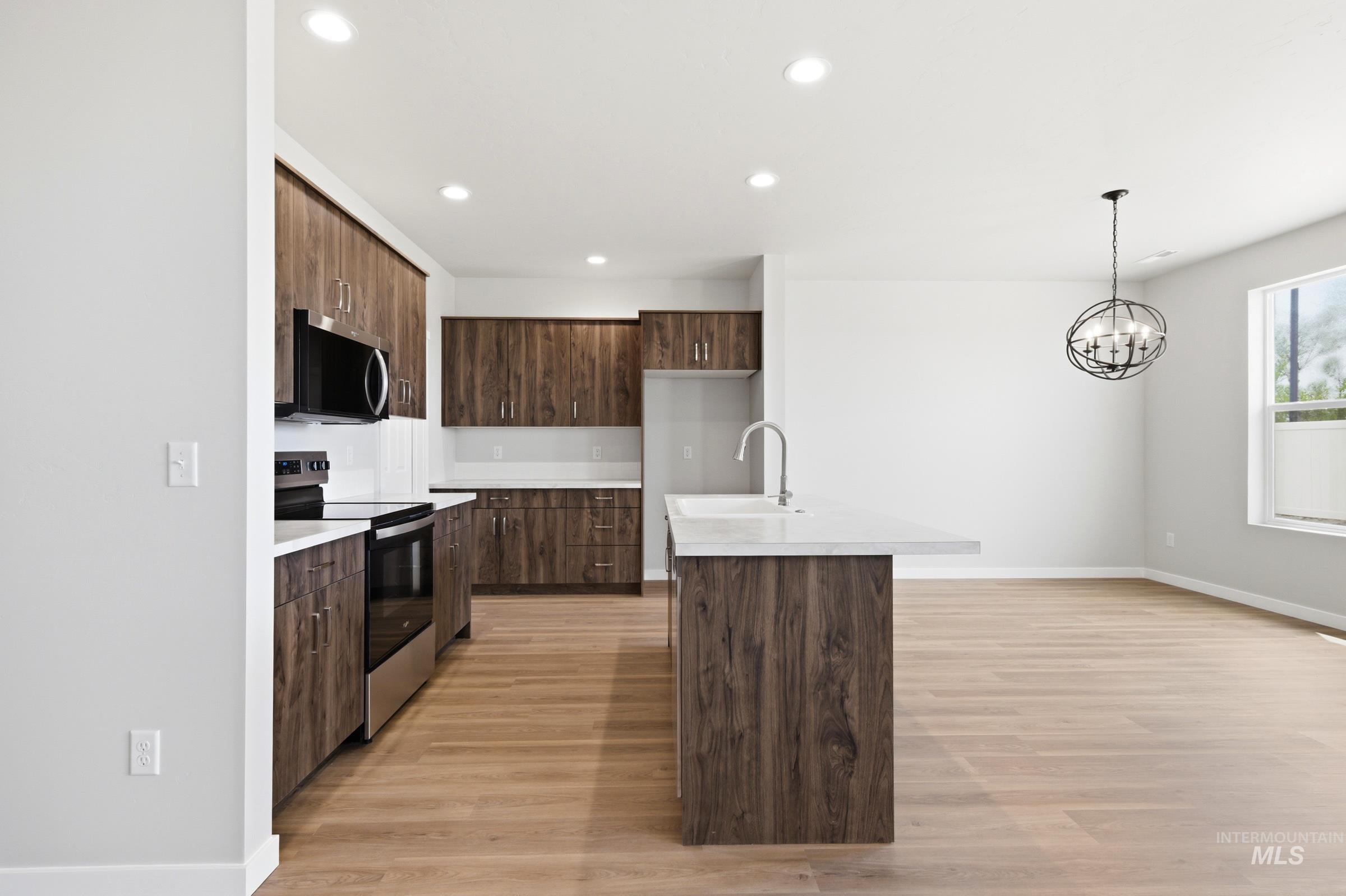 509 Waverly Avenue Middleton, ID 83644 - Photo 3 of 19 Contemporary kitchen featuring wood-finish cabinetry, stainless steel appliances, and a central island with an integrated sink