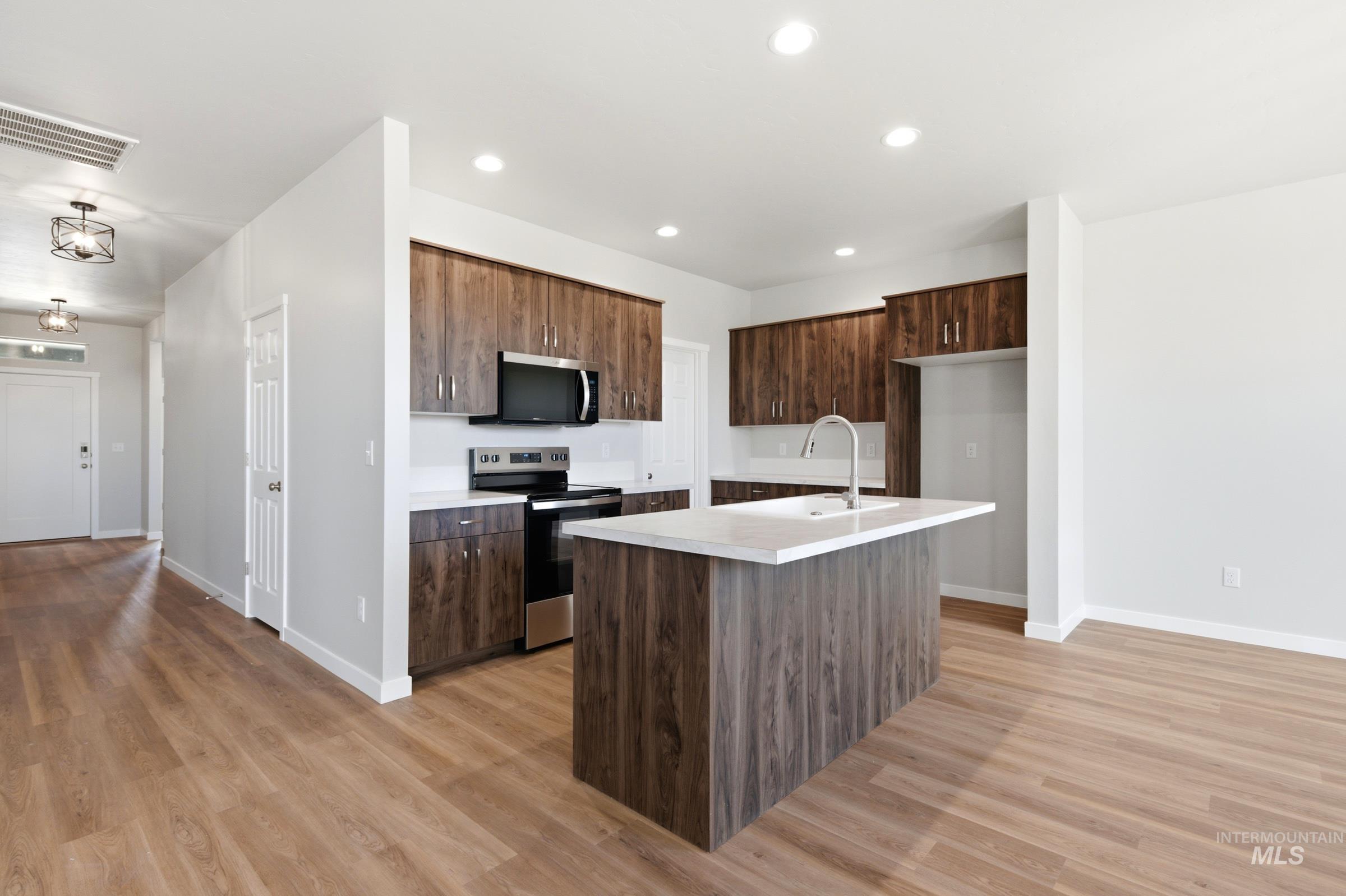 509 Waverly Avenue Middleton, ID 83644 - Photo 4 of 19 Kitchen featuring wood-finish cabinetry, stainless steel appliances, white quartz countertops, a kitchen island with an integrated sink, and recessed lighting