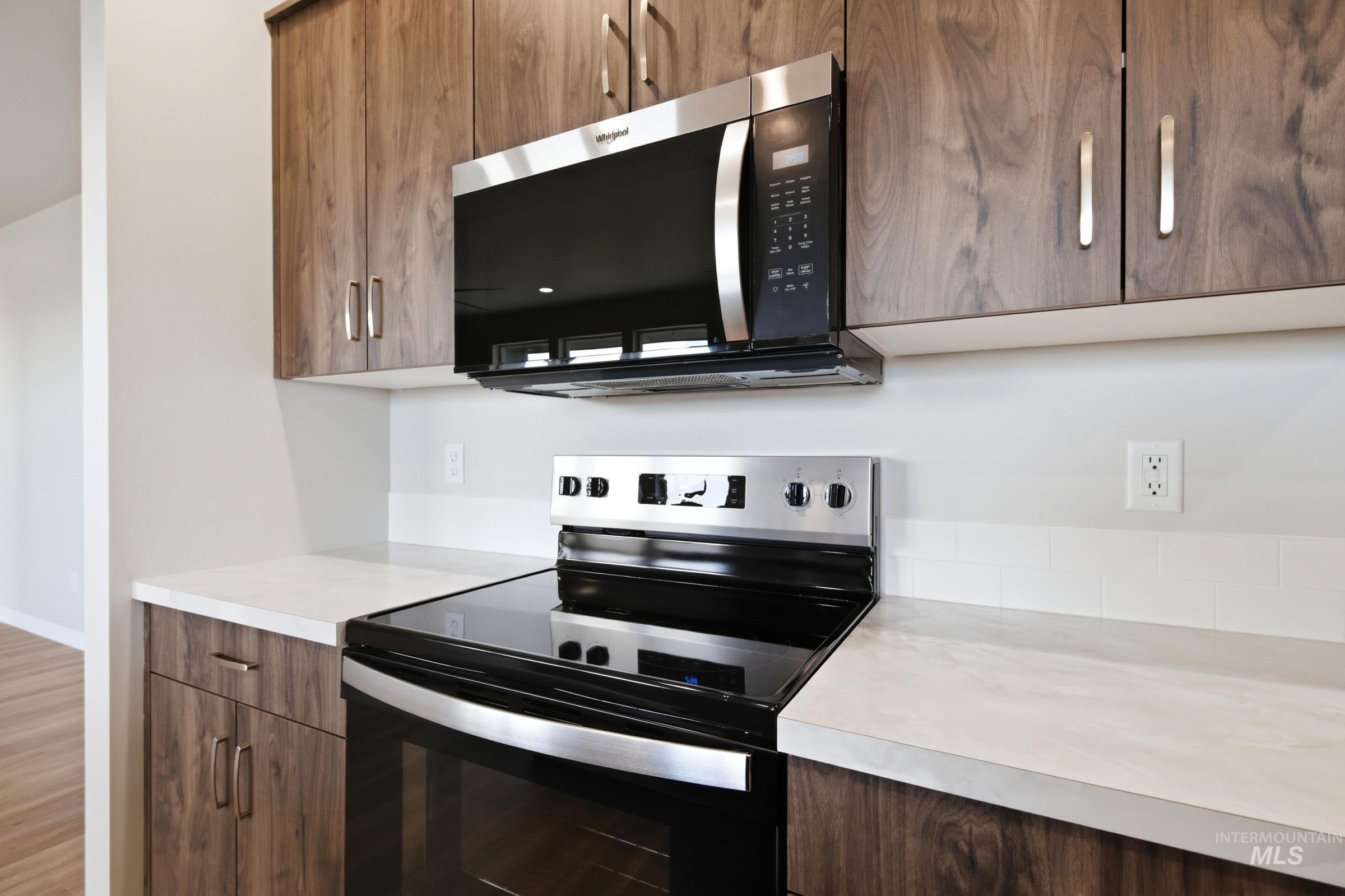 509 Waverly Avenue Middleton, ID 83644 - Photo 7 of 19 Modern kitchen featuring wood-grain cabinetry, stainless steel appliances, a white subway tile backsplash, and light-colored countertops