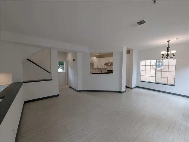 an empty room with chandelier and windows