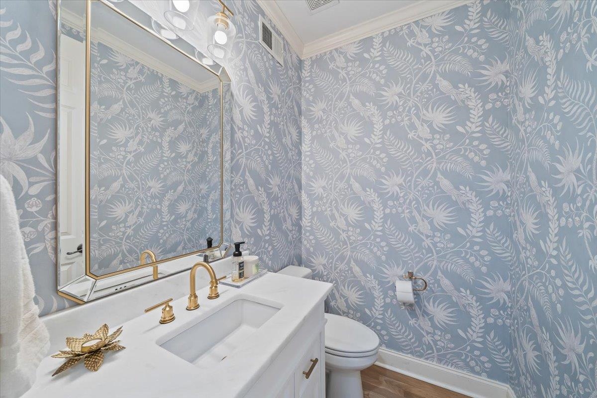 9455 Johnson Rd Extension Germantown, TN 38139 - Photo 16 of 40 Half bath featuring vanity, ornamental molding, dark wood-type flooring, and wallpapered walls