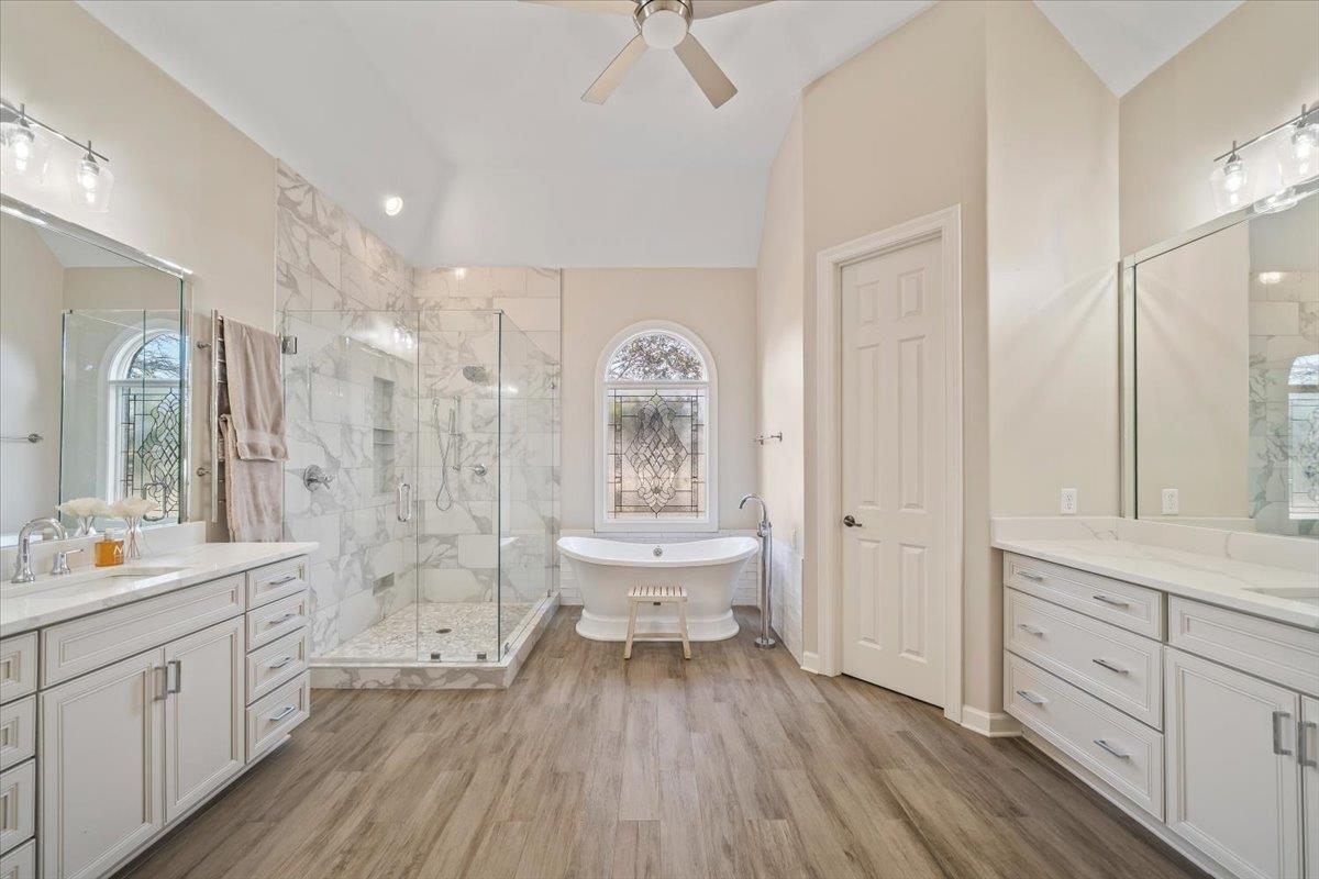 9455 Johnson Rd Extension Germantown, TN 38139 - Photo 20 of 40 Bathroom featuring two vanities, a shower stall, a freestanding tub, light wood-style floors, and a ceiling fan