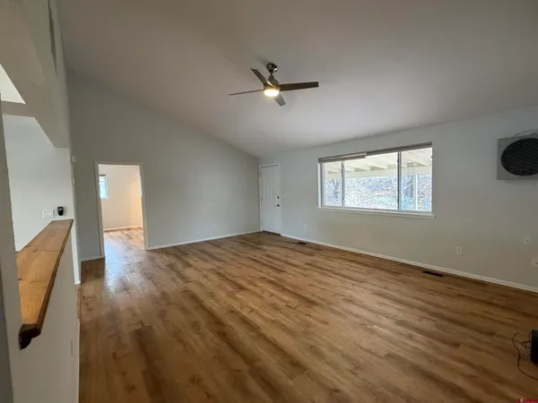 a view of an empty room with a window and wooden floor