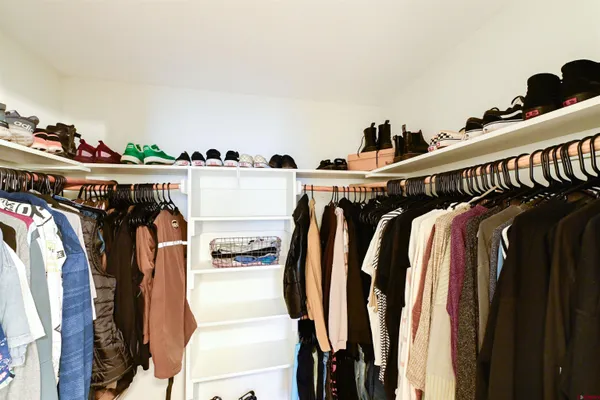a view of walk in closet with clothes and shoes