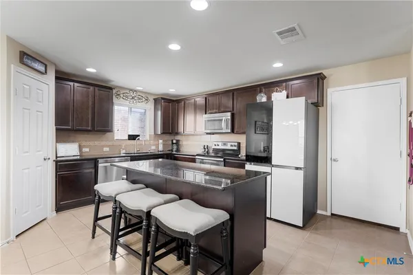 a kitchen with kitchen island granite countertop wooden cabinets and stainless steel appliances