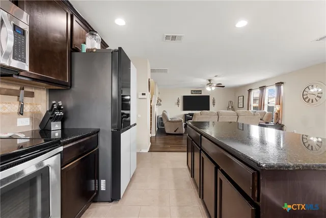 a kitchen with stainless steel appliances granite countertop a sink a stove and a refrigerator