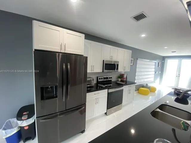 a kitchen with stainless steel appliances a sink dishwasher a refrigerator a microwave oven with granite countertops and cabinets