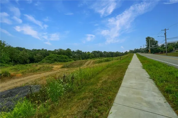 a view of a pathway both side of grassy field with shrub