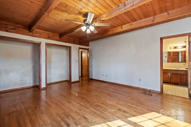 a view of an empty room with window and wooden floor