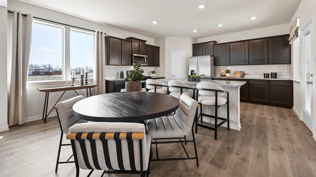 1305 Rusted Rail Drive Princeton, TX 75407 - Photo 31 of 35 a kitchen with stainless steel appliances kitchen island granite countertop a table chairs and a refrigerator