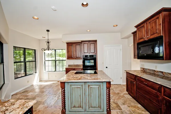 a kitchen with granite countertop a stove sink and microwave