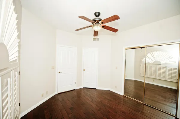 a view of empty room with wooden floor and fan