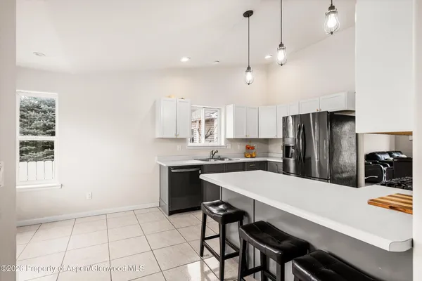 a kitchen with stainless steel appliances a table chairs and refrigerator