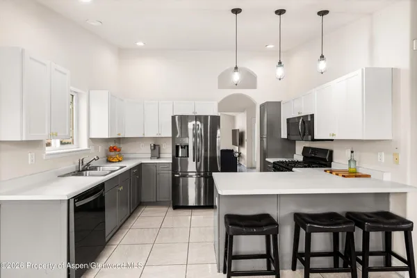 a kitchen with stainless steel appliances granite countertop a sink a stove a refrigerator and chairs