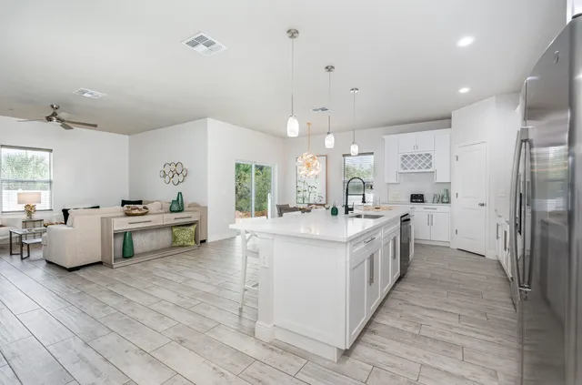 a large white kitchen with cabinets a sink and appliances