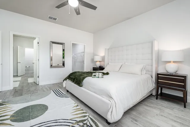 a bedroom with a bed a couch and a chandelier fan