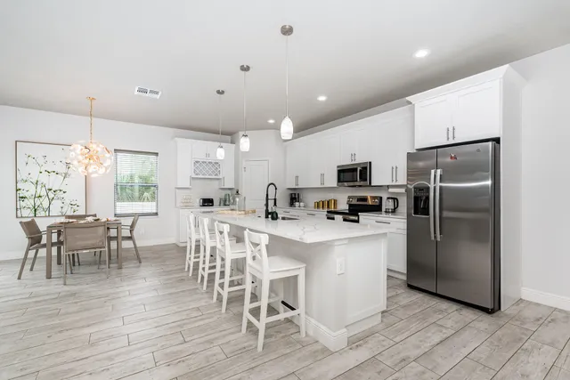 a kitchen with stainless steel appliances granite countertop a refrigerator a stove top oven a sink dishwasher a dining table and chairs with wooden floor