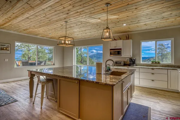 a kitchen with kitchen island granite countertop a sink a counter space appliances and cabinets