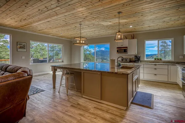 a kitchen with granite countertop a stove a sink dishwasher a dining table and chairs with wooden floor