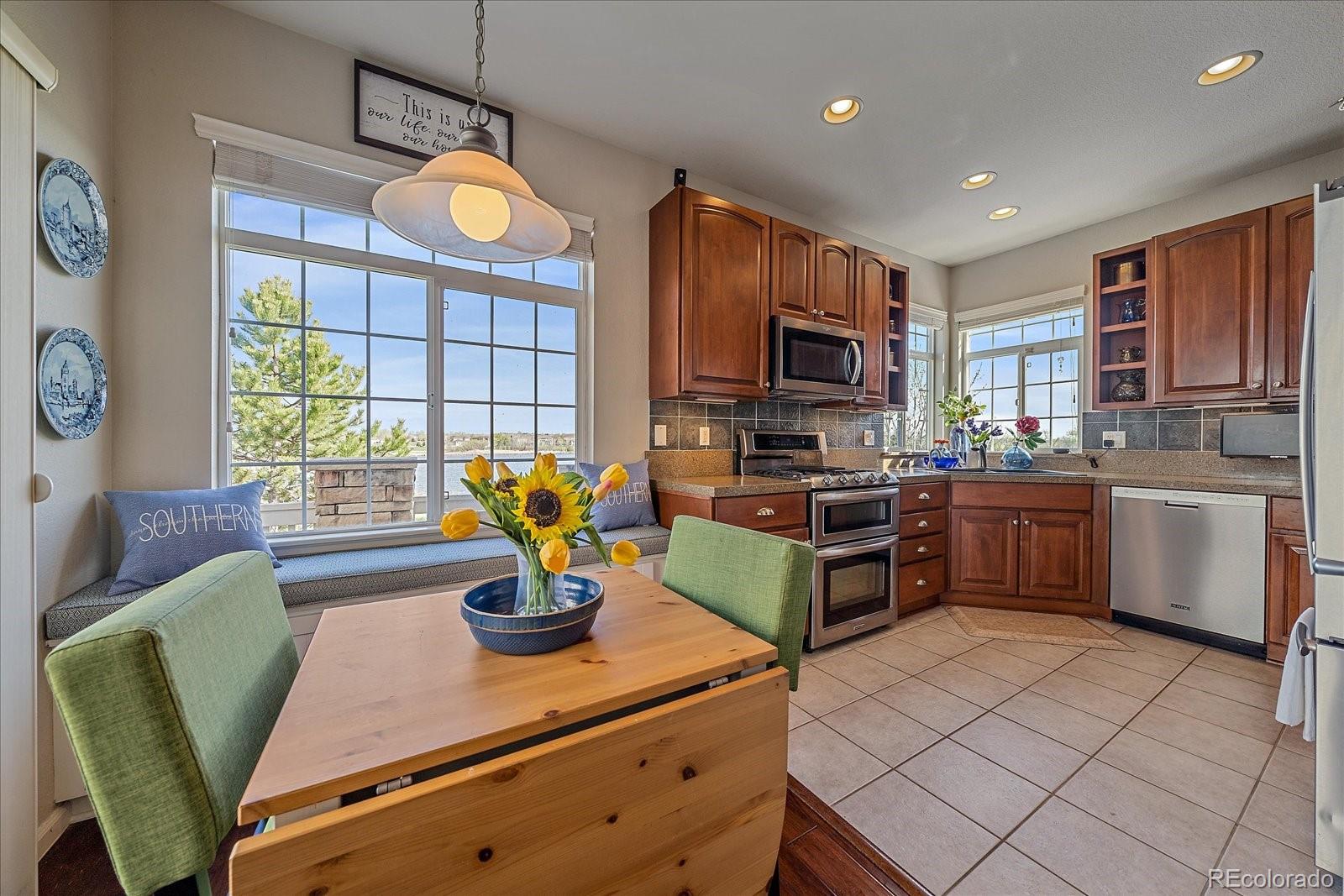 13721 Plaster Point, Unit 102 Broomfield, CO 80023 - Photo 8 of 35 a kitchen with stainless steel appliances kitchen island granite countertop a sink dishwasher a stove a refrigerator a microwave oven with granite countertops and a window