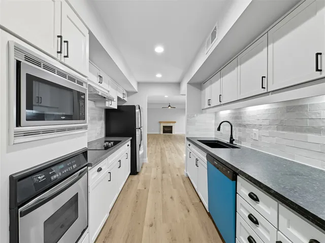 a large kitchen with stainless steel appliances granite countertop a sink a stove and cabinets